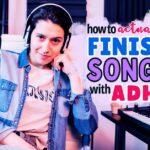 A confident music producer wearing headphones sits in a home studio surrounded by keyboards. Text overlay reads: "How to actually finish songs with ADHD" in colorful, bold fonts.